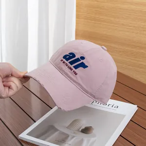 Detail of pink cotton baseball cap with blue suede 'air' lettering and frayed brim edges