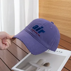 Close-up of purple cotton baseball cap featuring thick letter embroidery and distressed brim