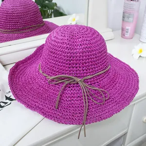 Detail of purple wide-brim woven straw hat with elegant brown ribbon bow decoration