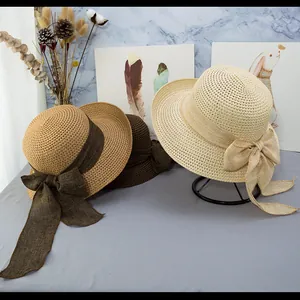 Dettaglio di cappelli in paglia intrecciata con grandi fiocchi in caffè, kaki e crema