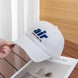 Detail of frayed brim cotton baseball cap with blue AIR embroidery on wooden surface