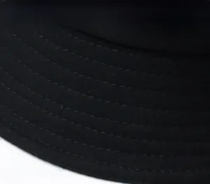Gros plan des coutures parallèles renforcées sur le bord d'un chapeau bob noir uni