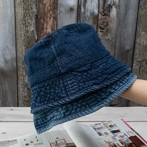 Vintage dark blue washed denim bucket hat with stitching details on a wooden background