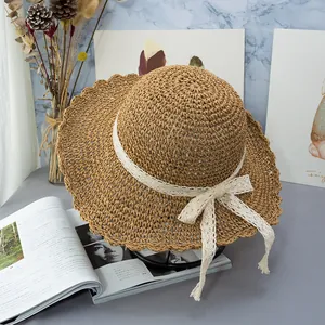 Dettaglio di un cappello di paglia intrecciato a mano con tesa a onde e fiocco in pizzo