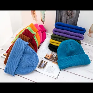 Gorros de punto desgastados en varios colores sobre madera blanca para invierno