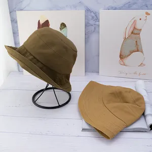 Close-up of canvas bucket hats in olive green and tan showing detailed reinforced stitching