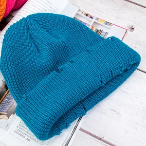 Gorro de punto azul oscuro con detalles desgastados sobre fondo de madera