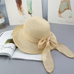 Vista dall'alto di un cappello di paglia beige con grande fiocco su sfondo estetico chic