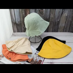 Double-sided cotton bucket hats in five colors including green, yellow, and black for sun protection
