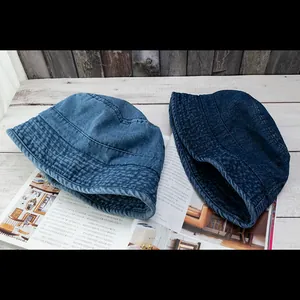 Washed denim bucket hats in light and dark blue styles displayed on a wooden table