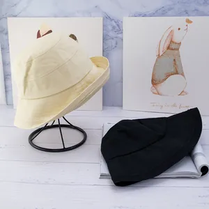 Detailed view of cream and black cotton bucket hats showing thick canvas texture and wide brim