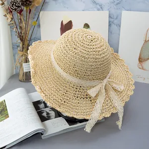 Dettaglio cappello di paglia beige con fiocco in pizzo e tesa ondulata stile vintage