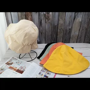 Reversible cotton sun hats in beige, yellow, orange, and green on wooden background