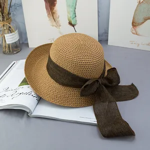Dettaglio cappello di paglia a tesa larga con fiocco marrone su rivista di moda