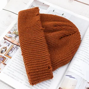 Detalle de gorro de punto color caramelo con diseño desgastado y textura de canalé en revista