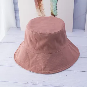 Detail of dust pink cotton bucket hat with multi-row stitched brim on a white table