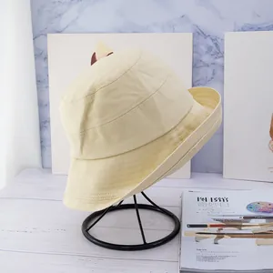 Detailed close-up of a beige cotton canvas bucket hat on a minimalist display stand