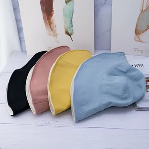 Foldable cotton bucket hats in four colors on a white wooden table for sun protection