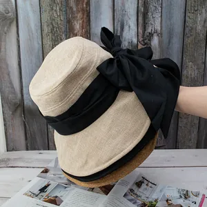 Detail of hand-woven straw hats in beige, black, and brown with a large black bow decor