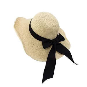 Women's summer straw sun hat with elegant wide black ribbon bow and wavy brim