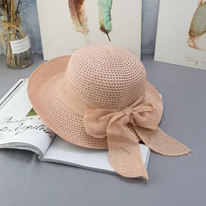 Dettaglio cappello di paglia rosa a tesa larga con fiocco grande e trama intrecciata