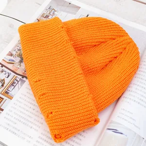 Primer plano de gorro de punto naranja brillante con detalles rotos de estilo urbano