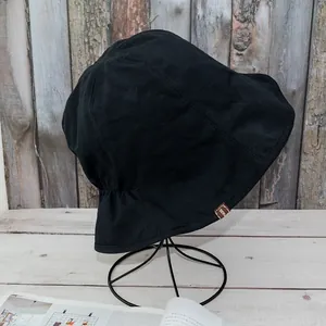 Close-up of black cotton sun hat with elastic back and brown 'MADE' cloth label
