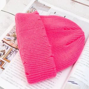 Primer plano de un gorro de punto acanalado rosa brillante con detalles desgastados en revista