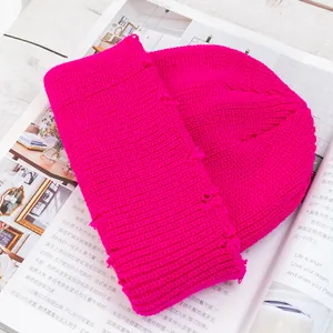 Detalle de un gorro de punto rosa intenso con canalé grueso y rotos de moda