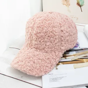 Detail shot of a soft pink fuzzy lamb wool baseball cap on a stylish white desktop