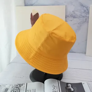 Detail of bright yellow cotton bucket hat with parallel brim stitching on a black stand