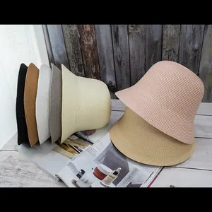 Bell-shaped woven straw bucket hats for women in seven colors on a wooden floor