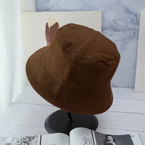 Detail view of brown cotton bucket hat with decorative stitching on the brim in studio