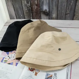 Foldable cotton bucket hats in black, khaki, and beige with metal M plaque detail