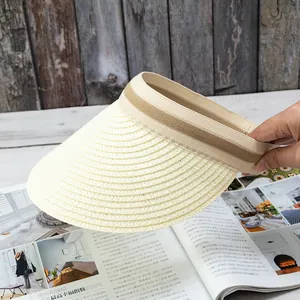 Close-up of woven straw sun hat with khaki ribbon detail on a vintage wood background