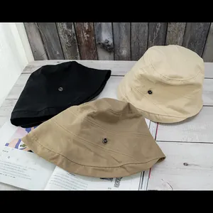 Close-up of three cotton bucket hats in black, khaki and beige with metal M logo detail