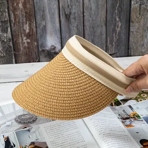 Detail of straw sun visor with striped ribbon on open magazine and wooden background