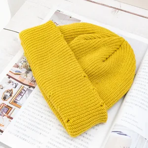 Detalle de gorro de punto amarillo con textura acanalada sobre revista de moda
