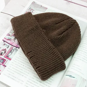 Primer plano del gorro de punto marrón mostrando la textura acanalada sobre madera