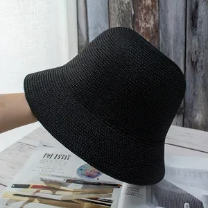 Detailed view of black woven straw bucket hat texture on minimalist wooden background