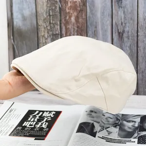 Detailed close-up showing the beige cotton twill fabric texture of the newsboy cap