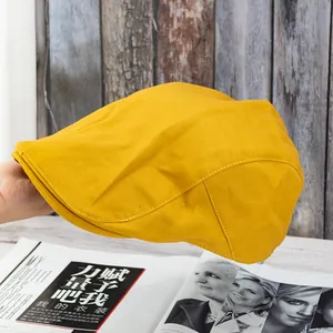 Detail view of ginger yellow cotton flat cap showing fine stitching and canvas texture