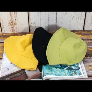 Vue détaillée de chapeaux bobs en coton jaune, vert et noir sur un magazine