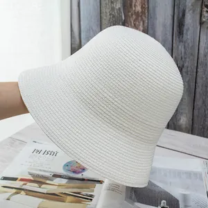 Detail of white finely woven straw bucket hat with textured spiral pattern and round top