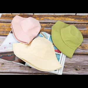 Vue de dessus de chapeaux de soleil en coton rose, beige et vert sur un bureau en bois
