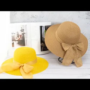 Détail de chapeaux en paille tissés main avec grands nœuds en jaune et naturel
