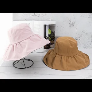 Detailed view of wide-brim sun hats in pink and brown with elegant pleated edge