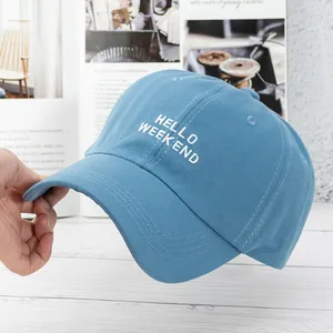 Detailed close-up of misty blue cotton baseball cap with white embroidered Hello Weekend text