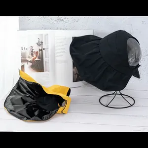 Close-up of wide brim sun hats in black and yellow on a white wooden background