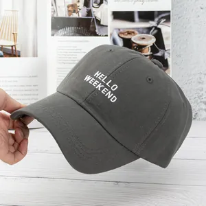 Detail of dark grey baseball cap featuring white HELLO WEEKEND embroidery and twill fabric